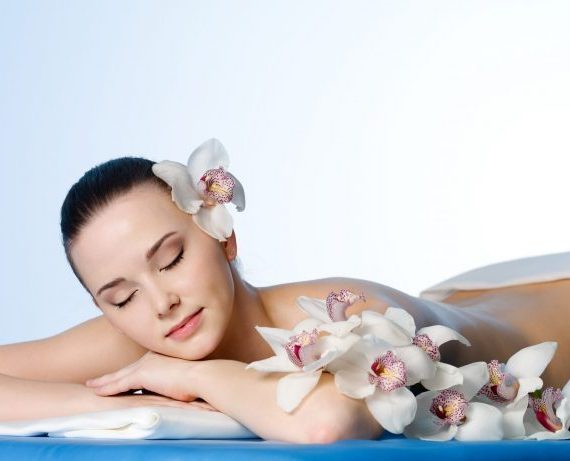 Woman resting in beauty spa salon  with flowers - colored background